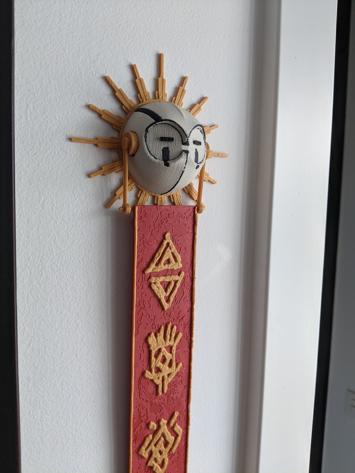 Decorative wall piece with sun and moon design on a white wall