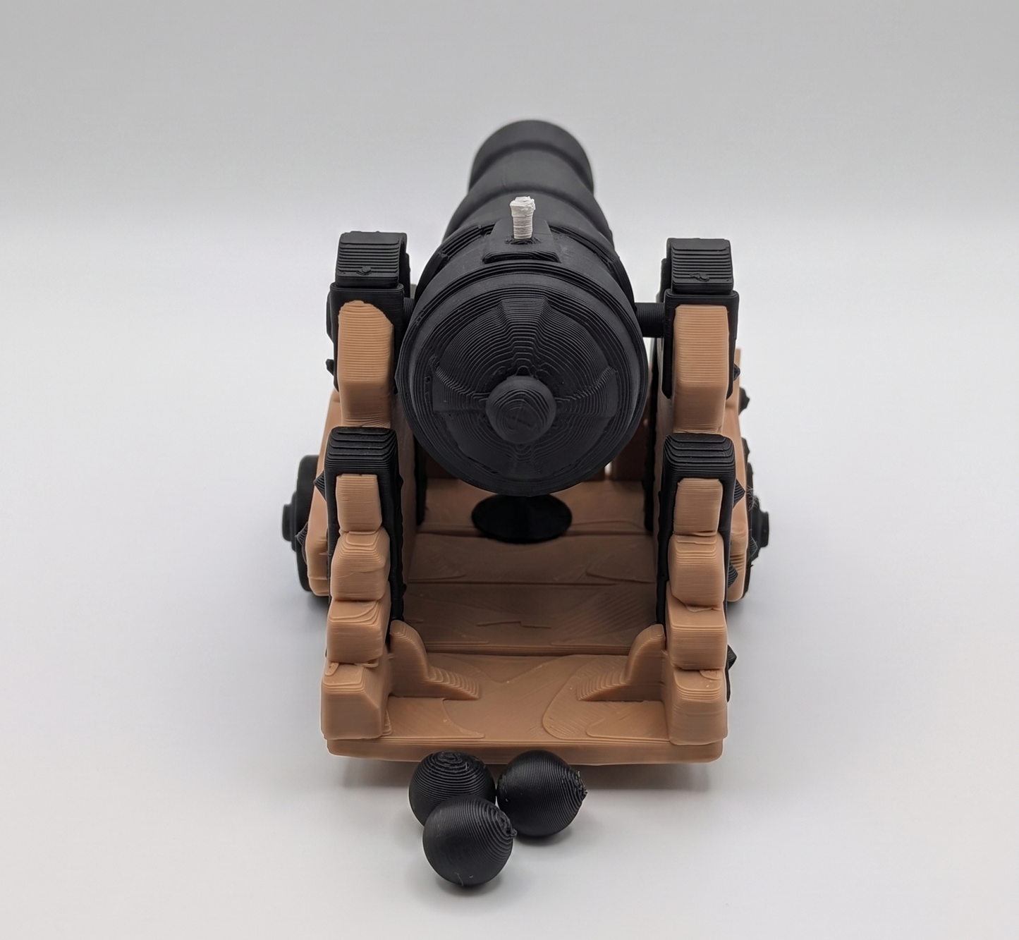 Toy cannon with a brown base and black barrel on a white background
