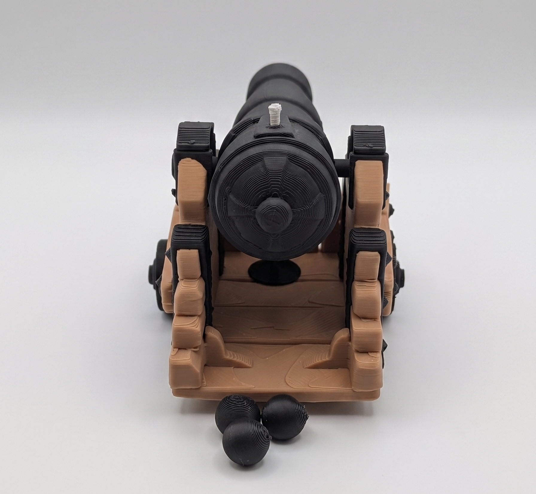 Toy cannon with a brown base and black barrel on a white background