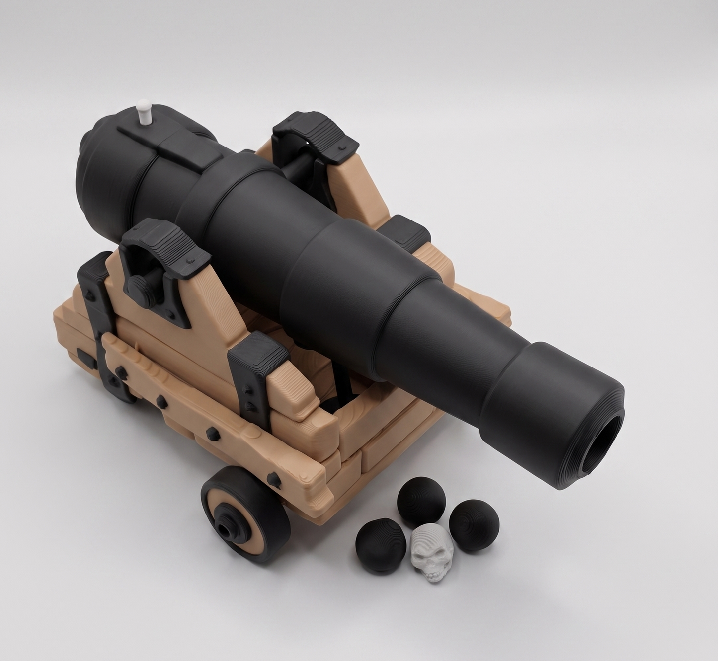 Toy cannon with black barrel and beige body on a white background